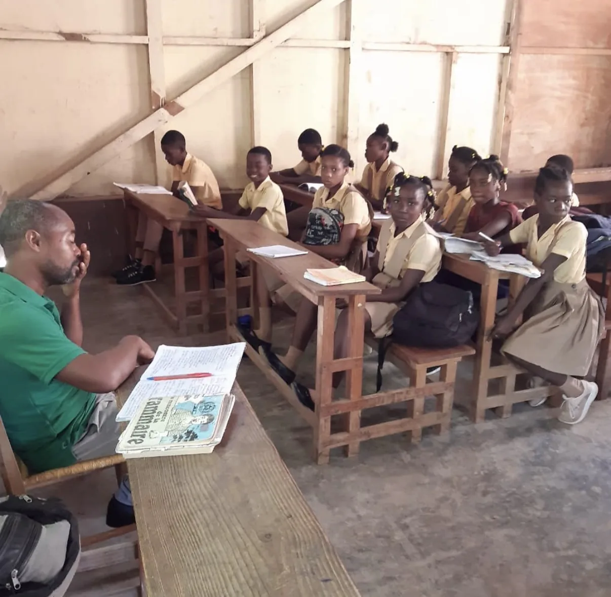 A staff member reads with students at their desks in an HEF classroom