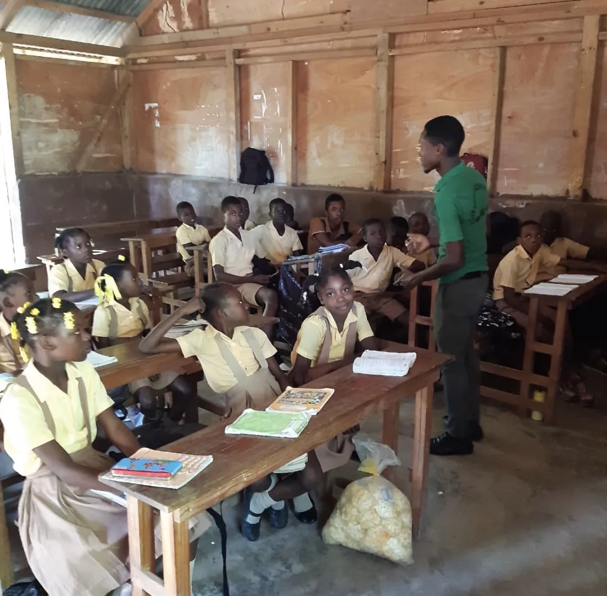 A teacher stands with his students at their desks in an HEF classroom